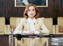 Rich lady sitting in front of a large desk with work papers on it. 