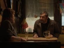 Two people discussing around a taable with beers.