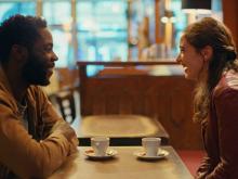 A man and a woman sitting in a coffee and laughing (still 2)