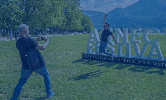 A man jumping in front of the Annecy Festival sign - ANNECY FESTIVAL/G. Piel